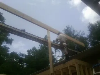 Carpenter setting a ridge beam over a new addition frame — Ice Dam Removal by Roofing Brothers in Fitzgerald