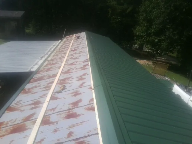 Old rusted panels beside newly installed green metal roofing — Wind Damage Roof Repair by Roofing Brothers in Fitzgerald