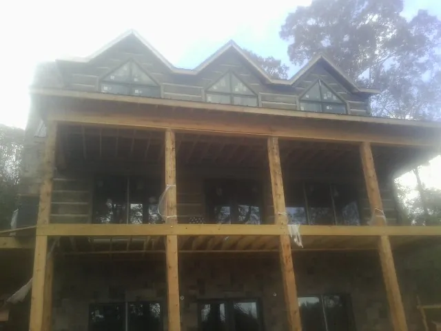Dormers and porch framing on a large log home under construction — Roof Coating work by our crew in Fitzgerald