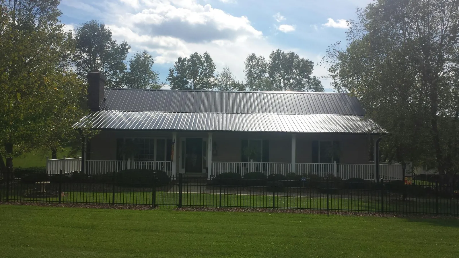 Gray metal roof on a brick ranch with a full width front porch — Gutter Guard Installation work by our crew in Fitzgerald