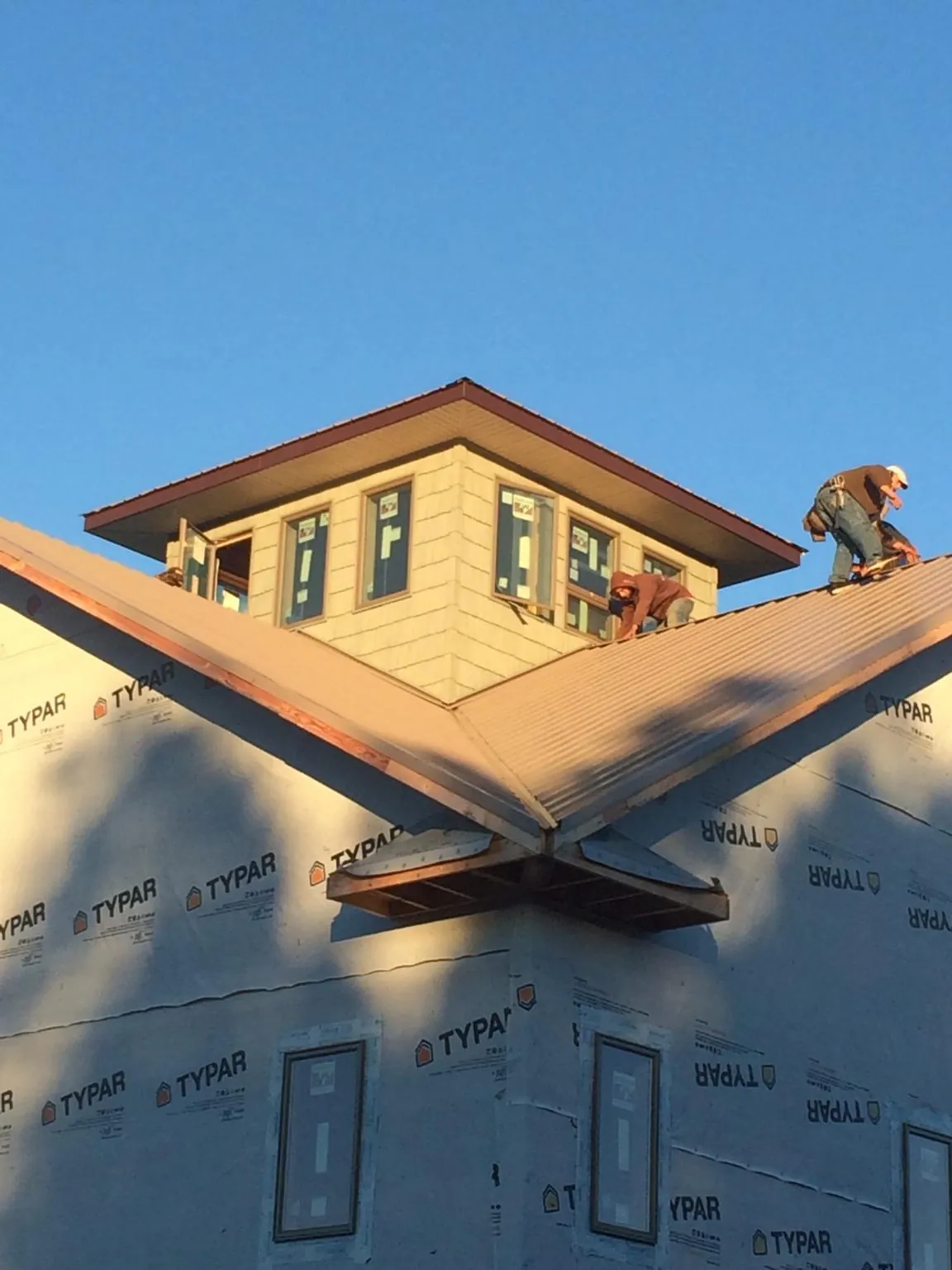 Roofers working around a rooftop cupola on a new metal roof at sunset — Roof Waterproofing in Fitzgerald by Roofing Brothers